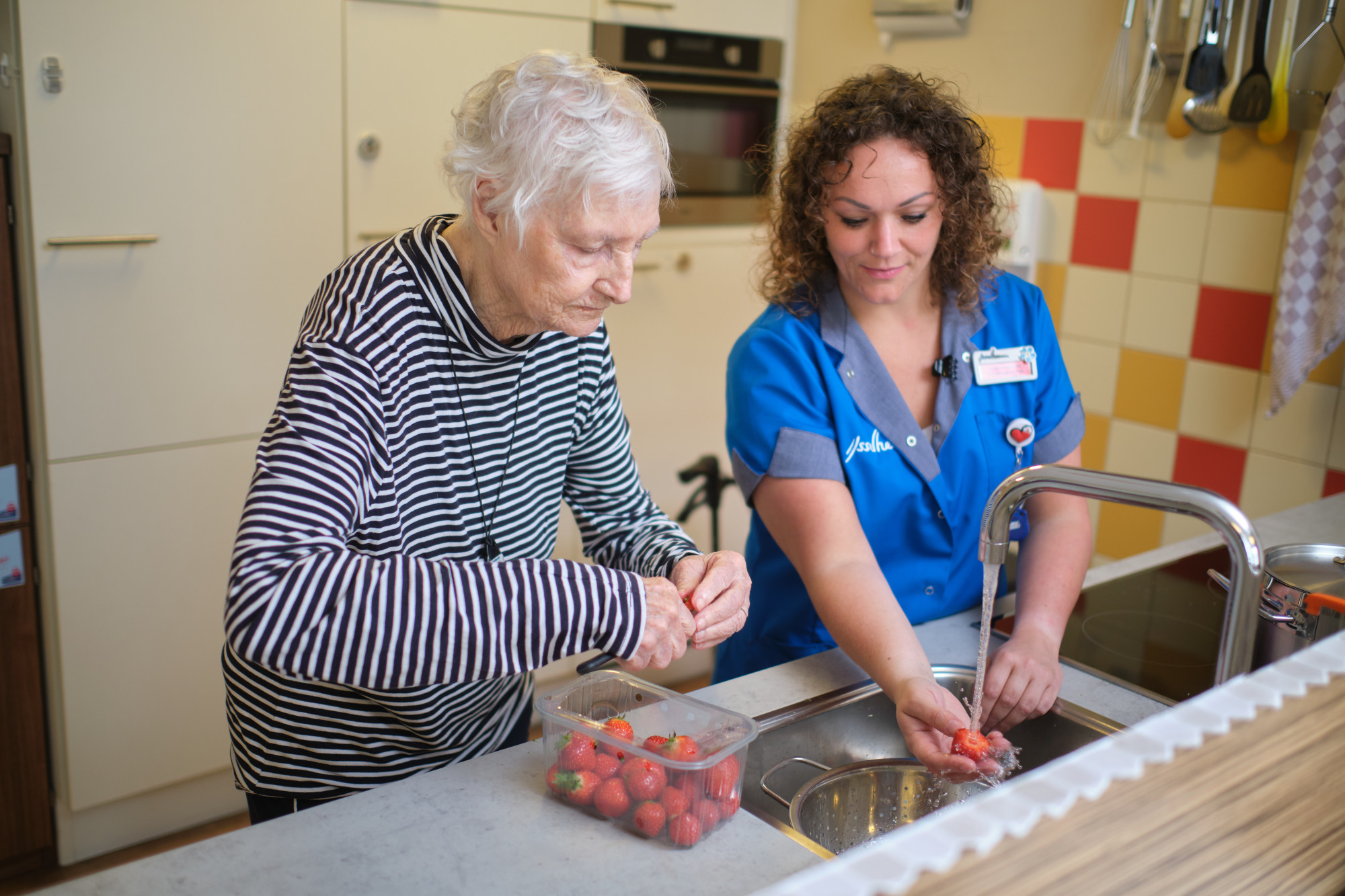 Cliënt en verzorgende staan bereiden aardbeien in de keuken