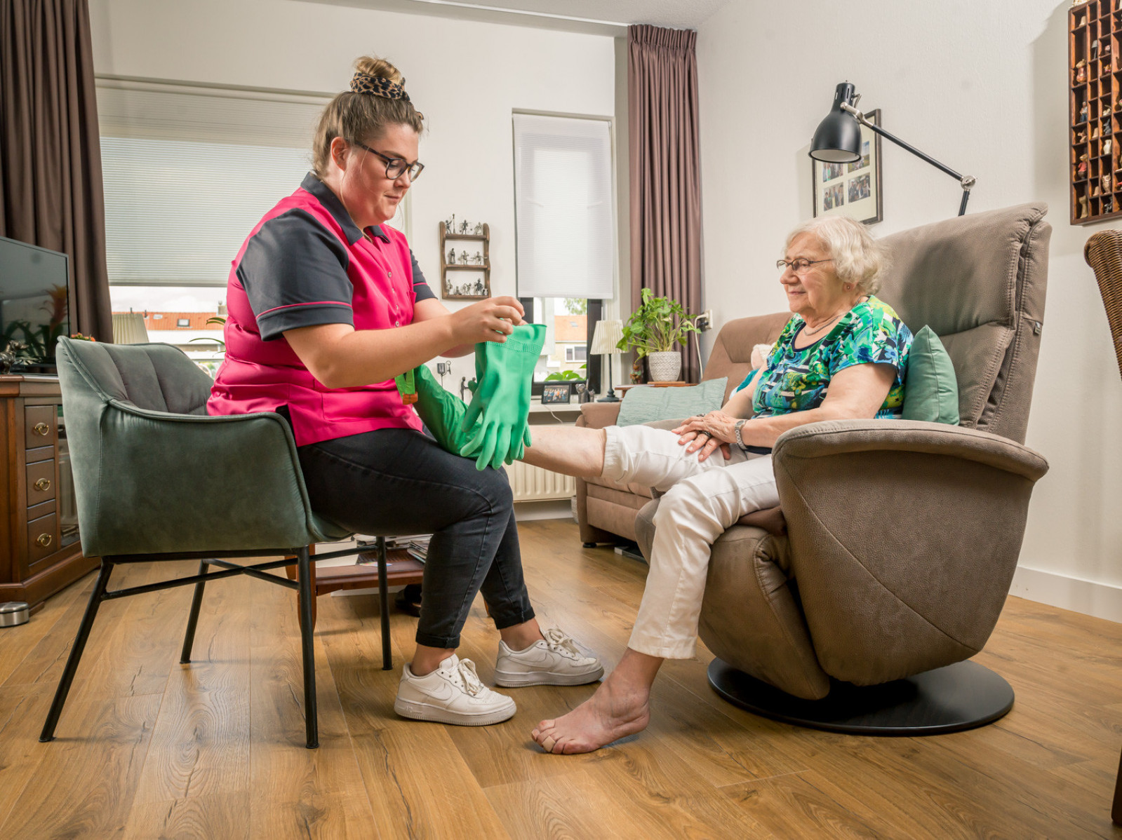 Wijkverpleegkundige helpt cliënt met steunkous aantrekken
